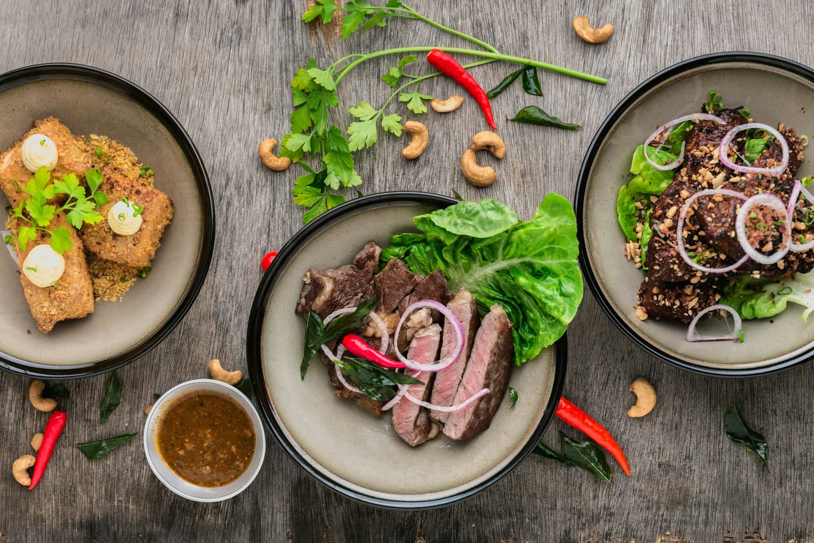 Shared plates of grilled meat and vegetables on a wooden table